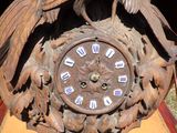une horloge en bois surmontée d'un oiseau