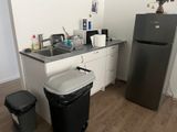 une cuisine équipée d'un réfrigérateur, d'un évier et d'une poubelle