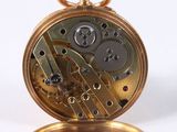a close up of a gold pocket watch on a white surface