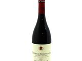 a bottle of red wine sitting on top of a white table