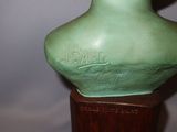 a green vase that is sitting on a wooden stand