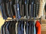 many jackets hanging on a rack in a clothing store