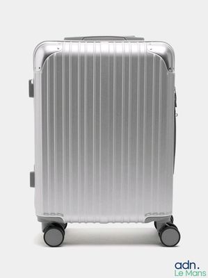 une valise argentée à roulettes sur fond blanc