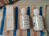two bottles of lotion sitting on top of a blue and white striped bag