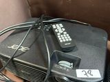 un projecteur avec une télécommande et d'autres appareils électroniques posés sur la table