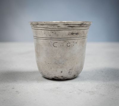 an old silver cup sitting on top of a white table