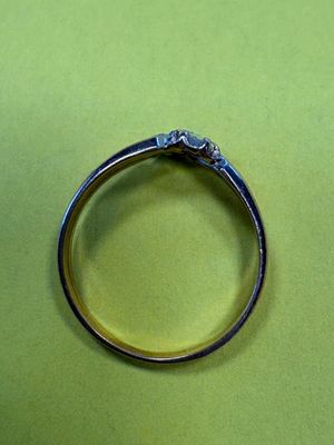 une bague en argent sertie d'un diamant, posée sur une surface verte