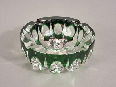 un cendrier en verre vert posé sur une table blanche