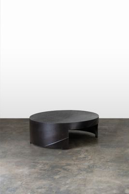 une photo d'une table basse noire posée sur un sol en béton