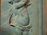 a statue of a baby holding a flower on the side of a building