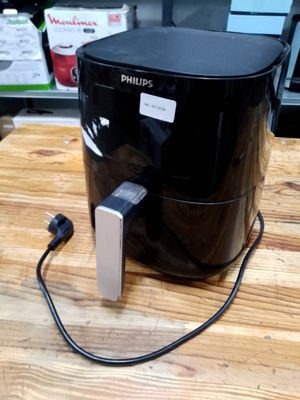 philips air fryer sitting on a wooden table with a power cord plugged into it
