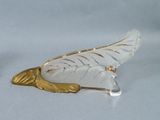 a white and gold feather shaped object on a white surface