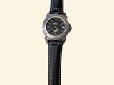 a watch that is sitting on top of a black strap