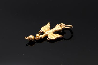 an image of a gold bird charm on a black surface