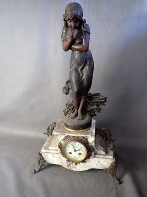 une statue de femme tenant une horloge sur une table