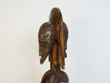 une sculpture en bois représentant un homme avec un oiseau sur la tête