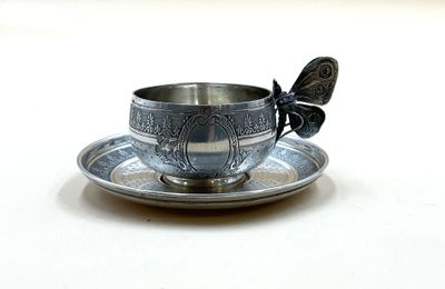 une tasse et une soucoupe en argent ornées d'un papillon
