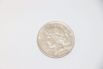 a silver coin on a white surface with a white background