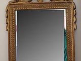 a mirror on the wall with a gold frame on it