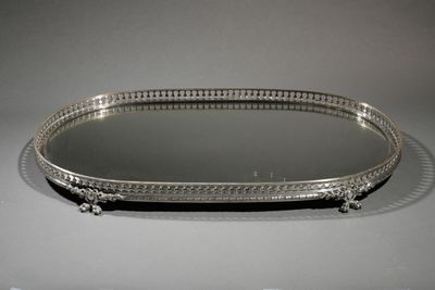an oval silver tray with a mirror on top of it