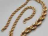 a close up of a gold chain on a white surface
