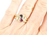an image of a woman ' s hand holding a gold ring with a purple stone