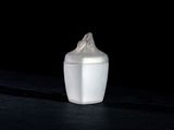 une petite tasse blanche avec un couvercle, posée sur une table