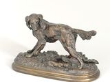 bronze statue of a dog on a rock on a white background