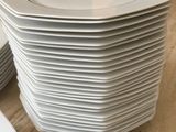 plusieurs assiettes blanches empilées les unes sur les autres sur une table en bois