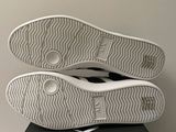 the soles of a pair of white sneakers are on a black box