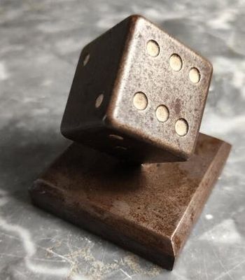 un dé en métal posé sur un bloc en bois