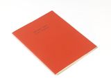 un cahier orange avec une inscription noire, posé sur une surface blanche