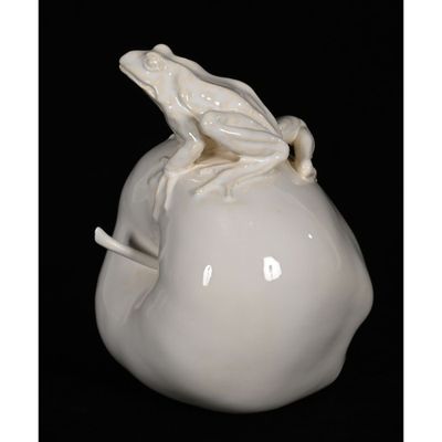 a white frog sitting on top of a white apple