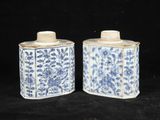 une paire de pots bleus et blancs ornés de motifs floraux sur fond noir