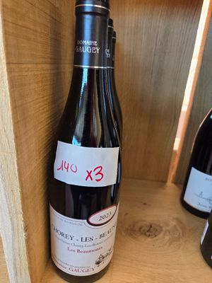 une bouteille de vin posée sur une étagère à côté de deux bouteilles de vin