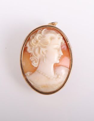 un gros plan sur le visage d'une femme dans une broche en or