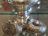 deux bagues en argent posées sur une table en verre, à côté d'un vase en argent