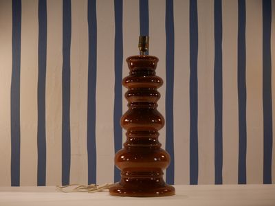 a lamp that is sitting on a table in front of a striped wall