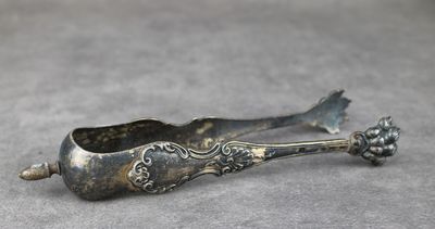 cuillère ancienne en métal argenté, ornée d'un motif floral sur un fond gris