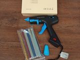un pistolet à colle sans fil et un paquet de bâtons de colle posés sur une table