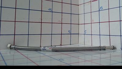 une photo d'une salle de bains avec un tuyau de douche posé par terre