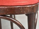 a close up of a wooden chair with a red cushion