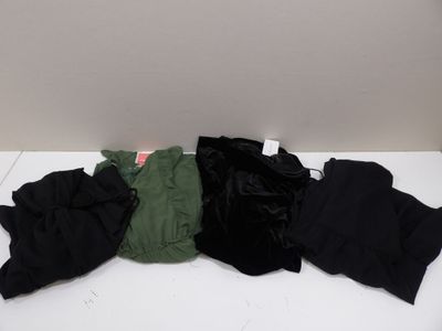 trois paires de pantalons noirs et verts posées sur une table blanche