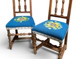 two wooden chairs with a blue seat and a floral design on the back
