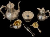 a silver tea set with spoons and spoons on the table