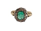gros plan d'une bague avec une pierre verte entourée de diamants