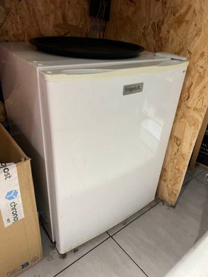 un petit réfrigérateur blanc dans le coin d'une pièce