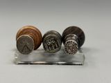 quatre types de boutons différents posés sur un support transparent posé sur une surface blanche