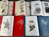 several books are lined up on a table with a drawing of a man