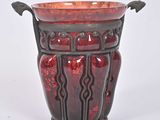 un vase rouge posé sur une surface blanche